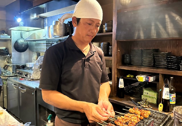 Yakitori master Isao grilling skewers over charcoal at his restaurant in Kobe, Japan