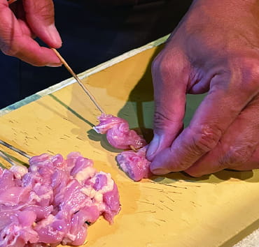 Skewering chicken for yakitori